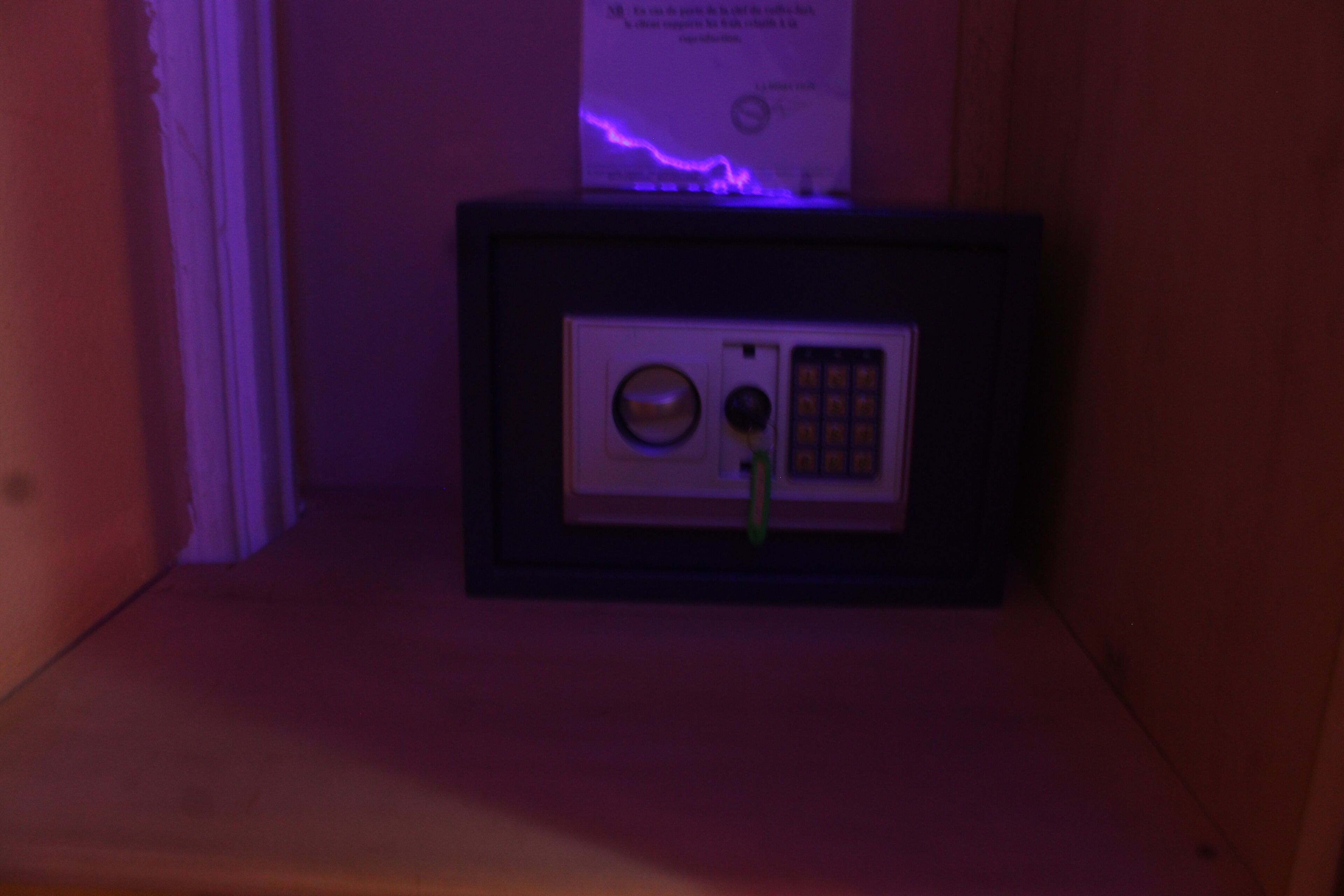 A small, dark room with a framed object on a shelf, possibly a safe or a decorative item.