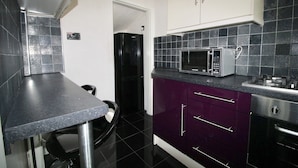 A compact kitchen with a black countertop, a microwave, and a stainless steel oven.