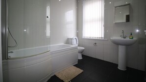 A modern bathroom with a bathtub, toilet, and sink.