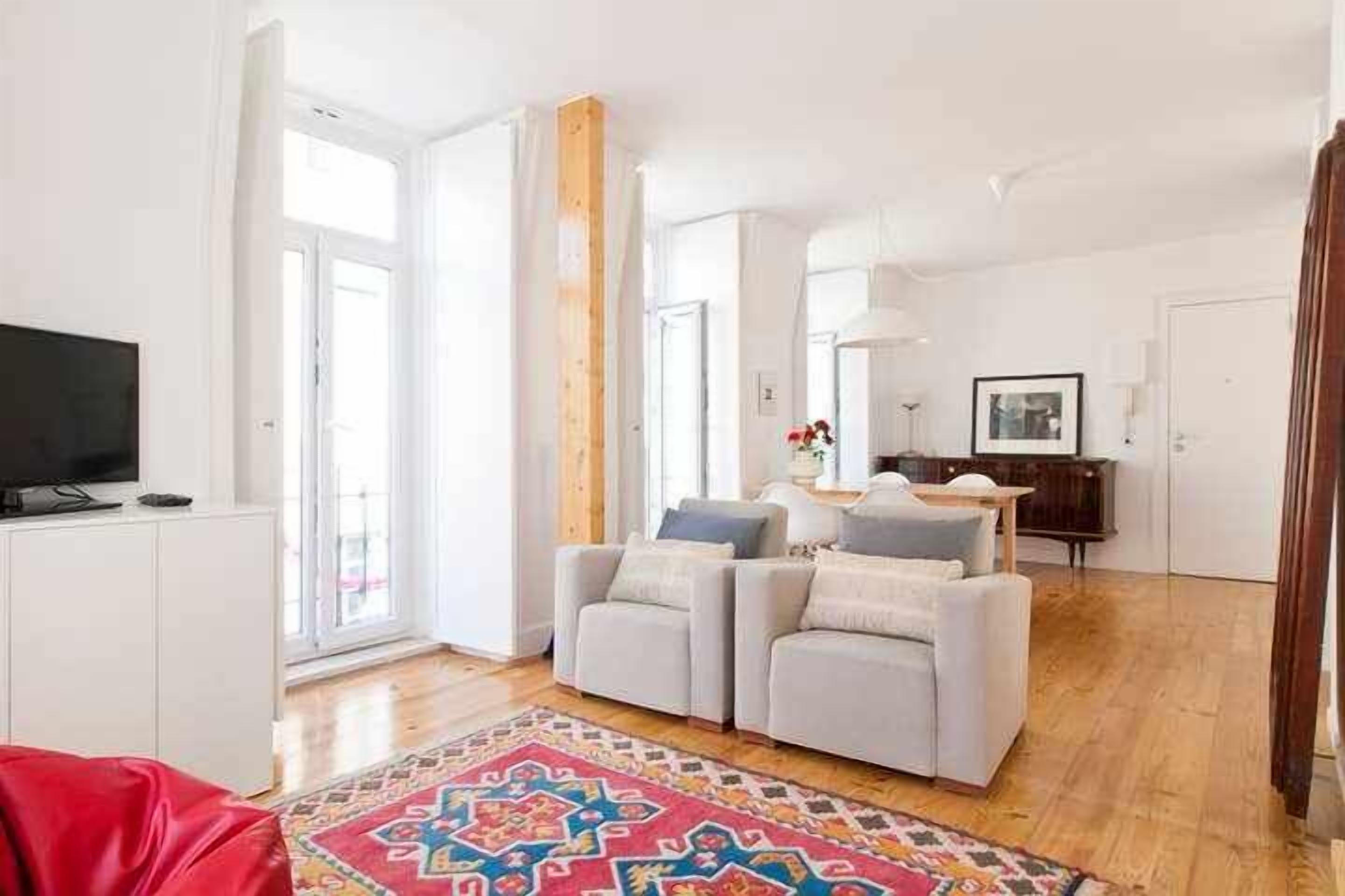 Una sala moderna con un conjunto de sofás, un televisor y una alfombra estampada.