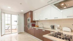 A modern kitchen with a built-in oven, a coffee maker, and a toaster. - Elegant in Alfama with Terrace and FREE parking. (Lisboa)