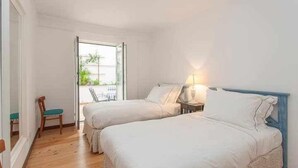 A bedroom with two beds, a chair, and a nightstand with a lamp. - Elegant in Alfama with Terrace and FREE parking. (Lisboa)