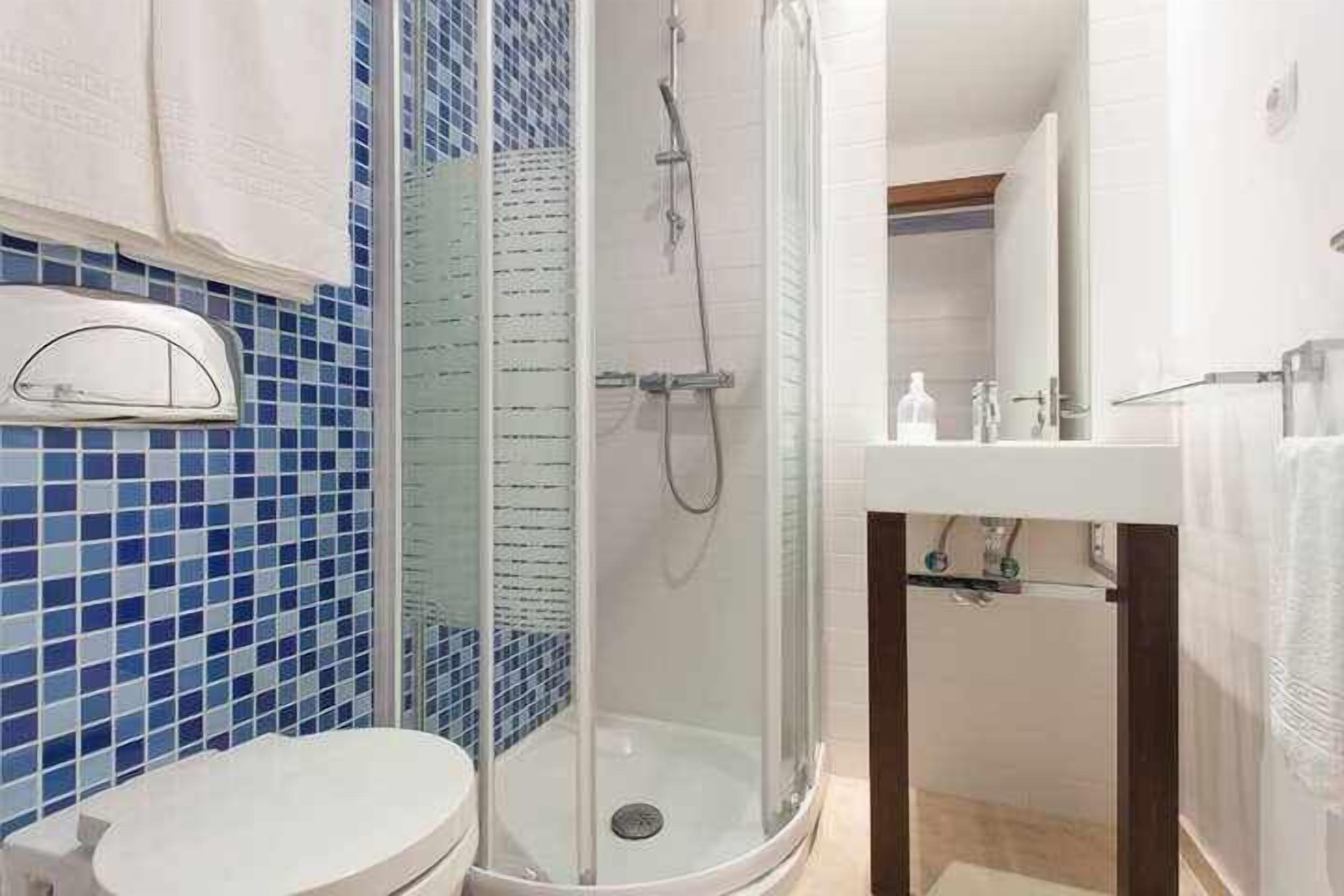 Un bagno con doccia vetro, WC bianco e lavabo con specchio.