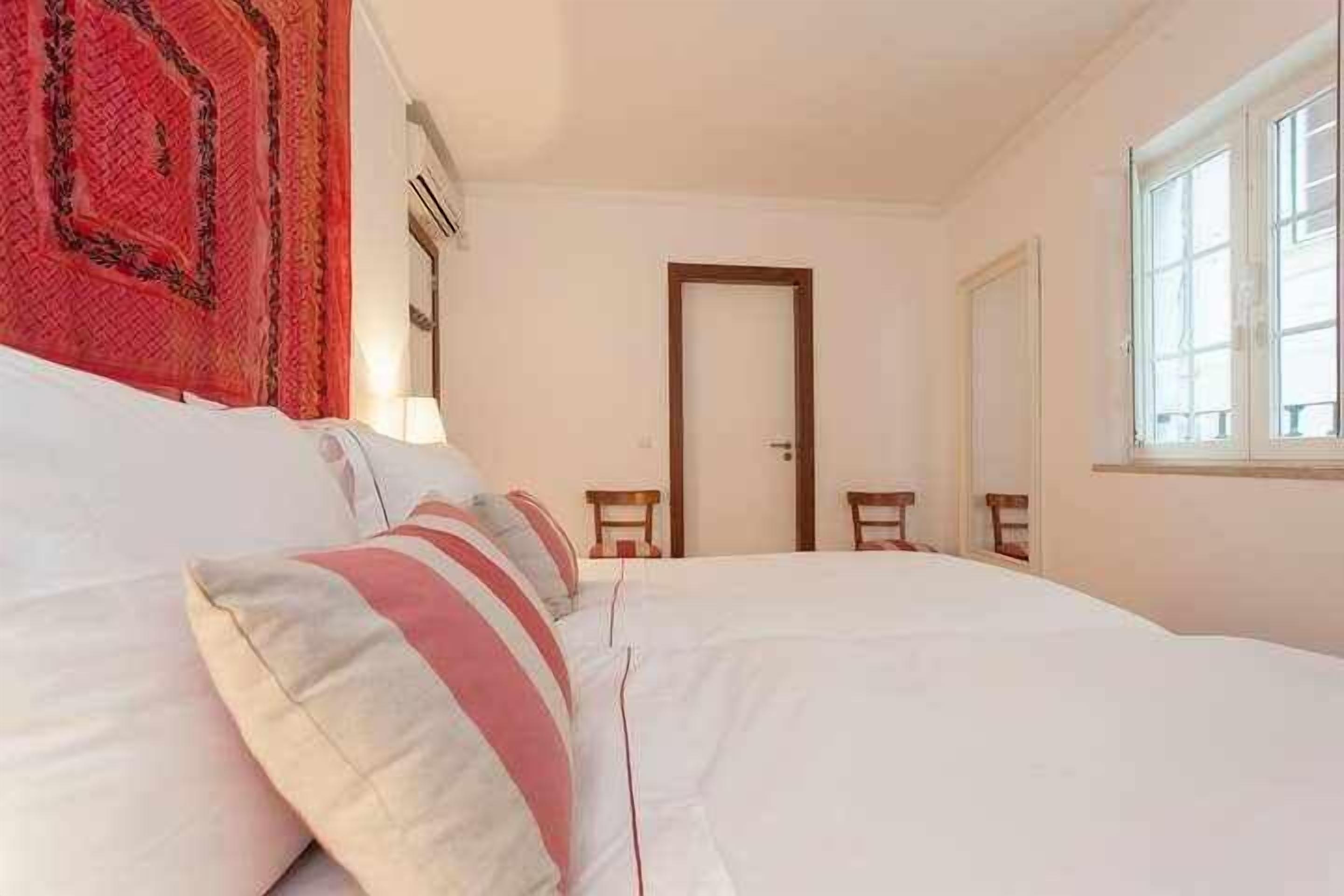 Une chambre d’hôtel avec un grand lit, une porte, une fenêtre et une petite table.
