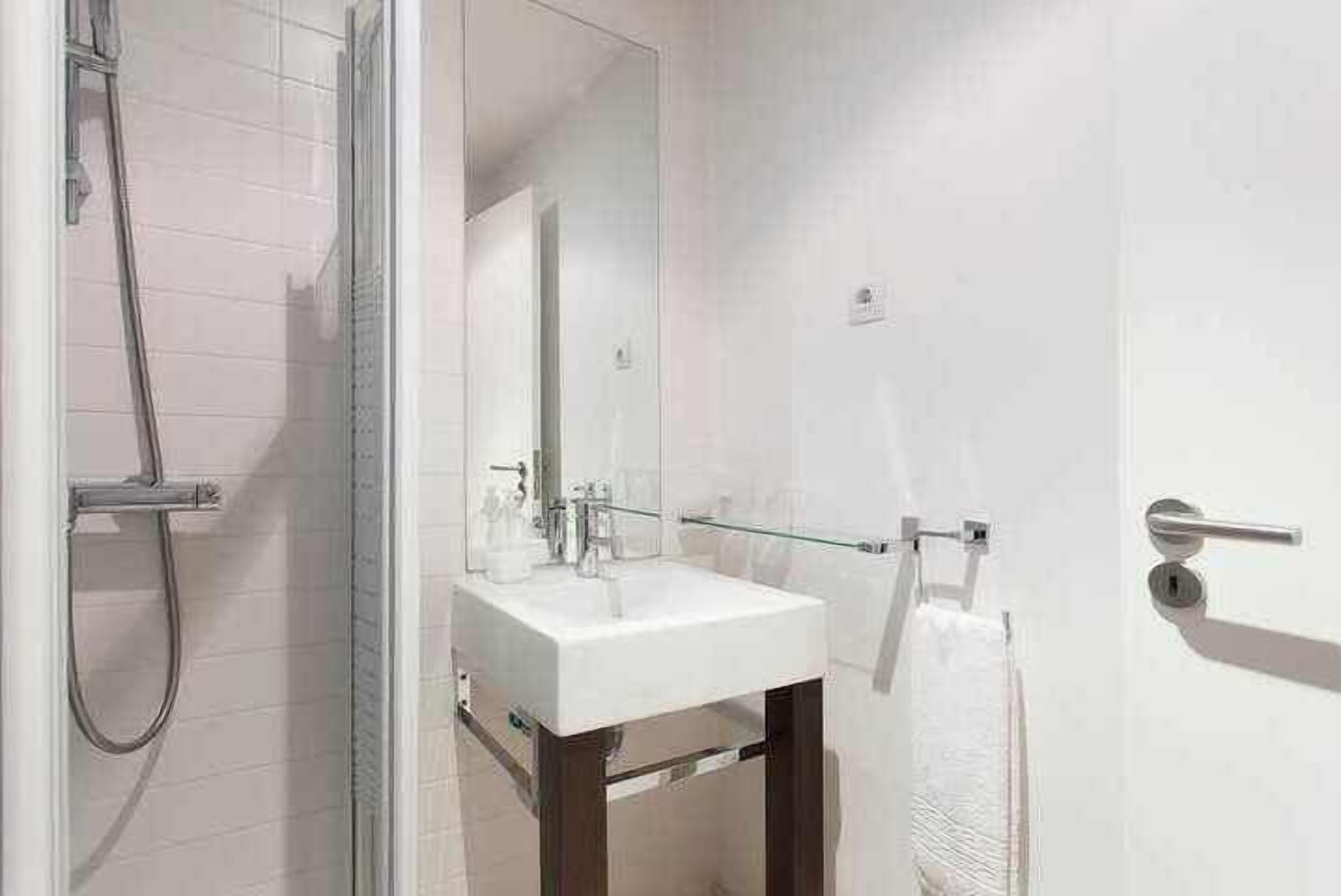 A modern bathroom with a glass shower enclosure, a white sink, and a mirror.