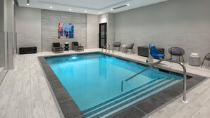 A modern indoor swimming pool with clear water, surrounded by lounge chairs and a tiled floor. - Holiday Inn Express Boston Logan Airport - Revere by IHG (Revere)