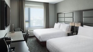 A hotel room with two beds, a desk, a chair, a TV, and a large window with curtains. - Holiday Inn Express Boston Logan Airport - Revere by IHG (Revere)