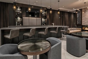 A modern bar area with a long counter, multiple bar stools, and a round glass table.