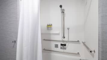A modern bathroom with a walk-in shower, grab bars, and a mounted soap dispenser.
