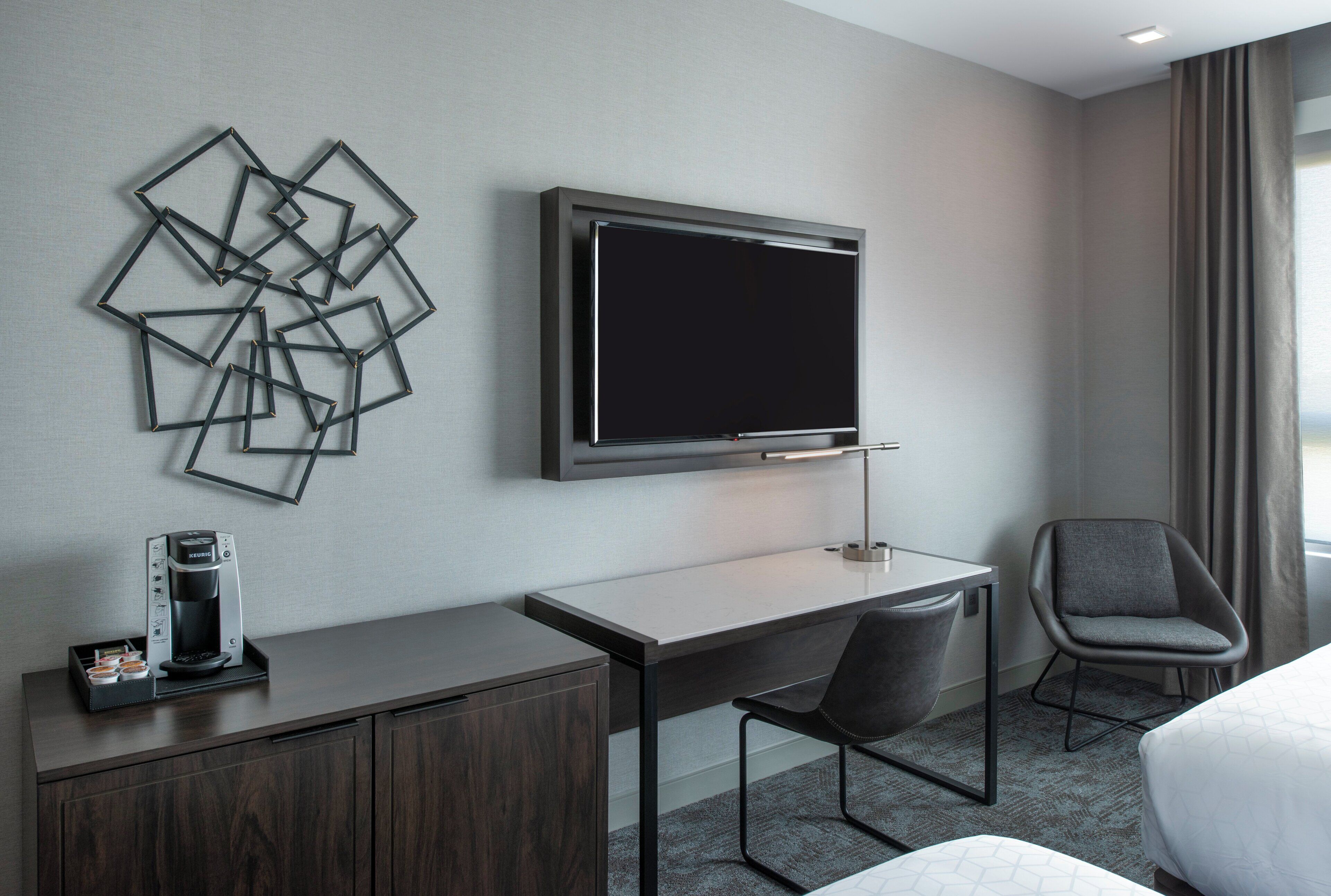 Une chambre d’hôtel équipée d’un bureau, d’une chaise, d’une télévision et d’une machine à café.