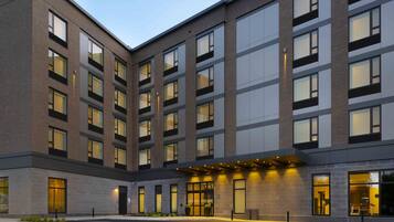 Um hotel de vários andares com design moderno, com grandes janelas e uma entrada bem iluminada.