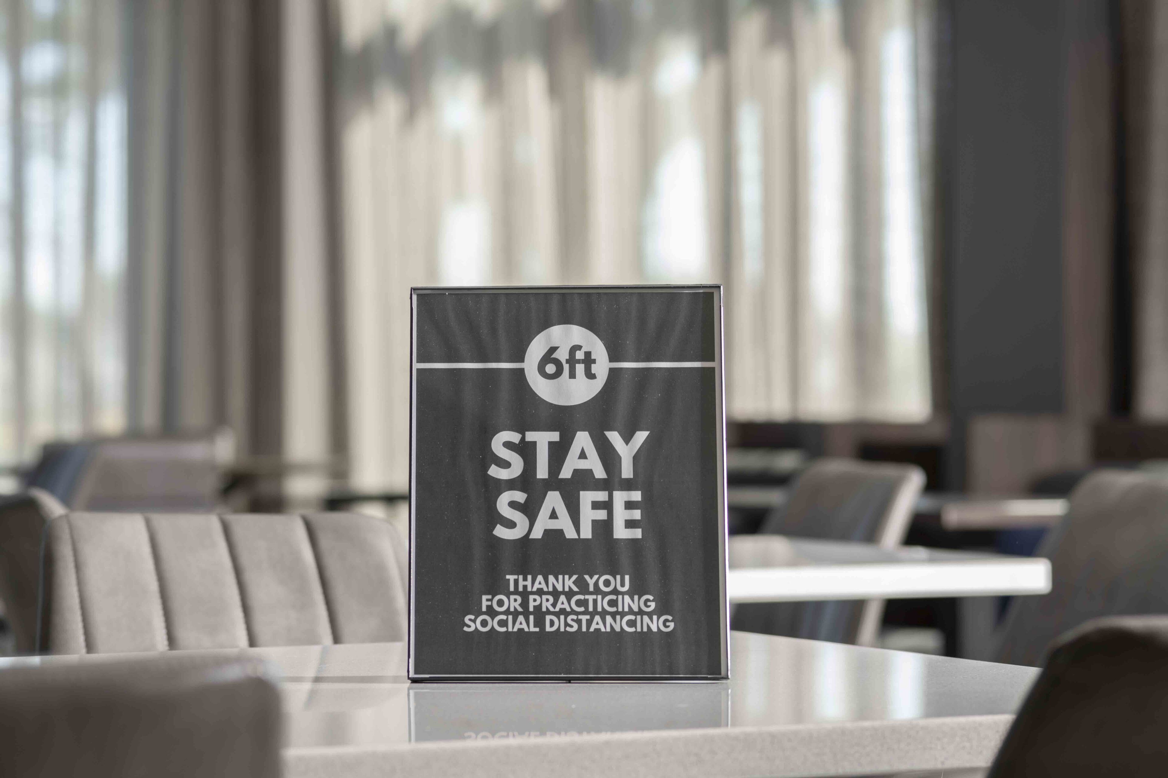 Señal en el vestíbulo de un hotel que indica una distancia de seguridad de 6 pies.