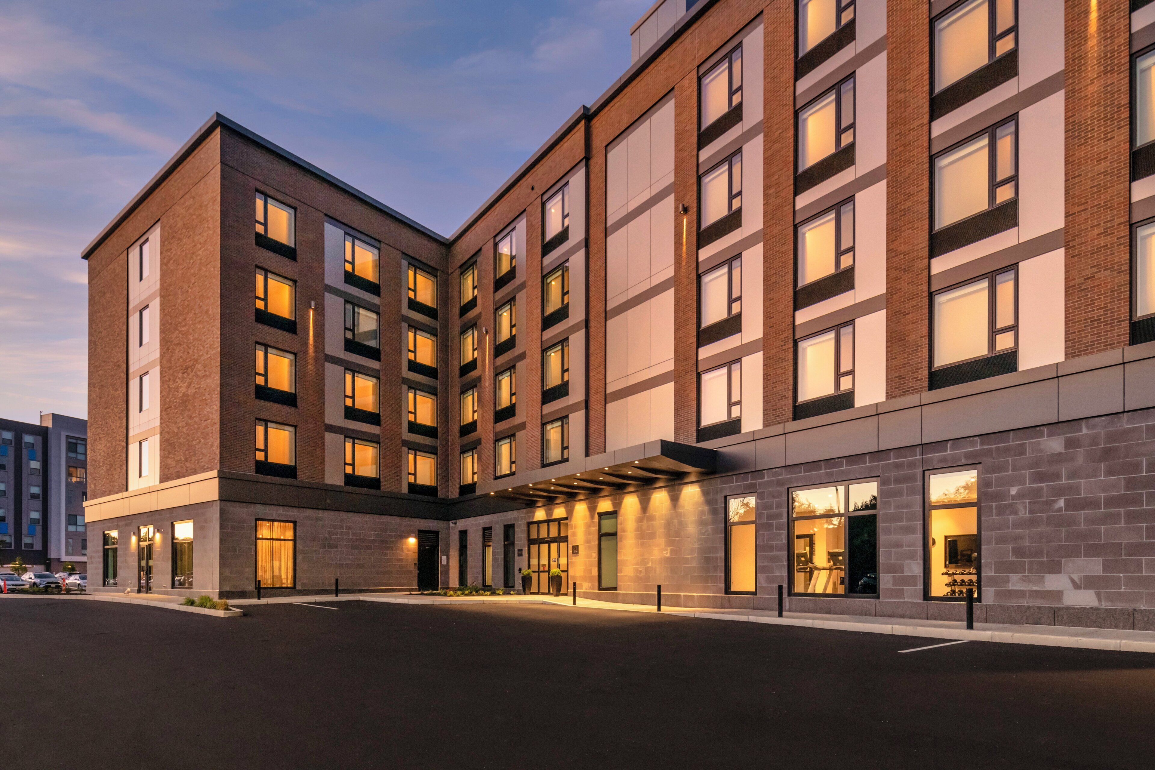 Un hotel a più piani dall'architettura moderna, caratterizzato da un ingresso principale con vetrate e una facciata ben illuminata.