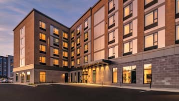 Un hotel a più piani dall'architettura moderna, caratterizzato da un ingresso principale con vetrate e una facciata ben illuminata.