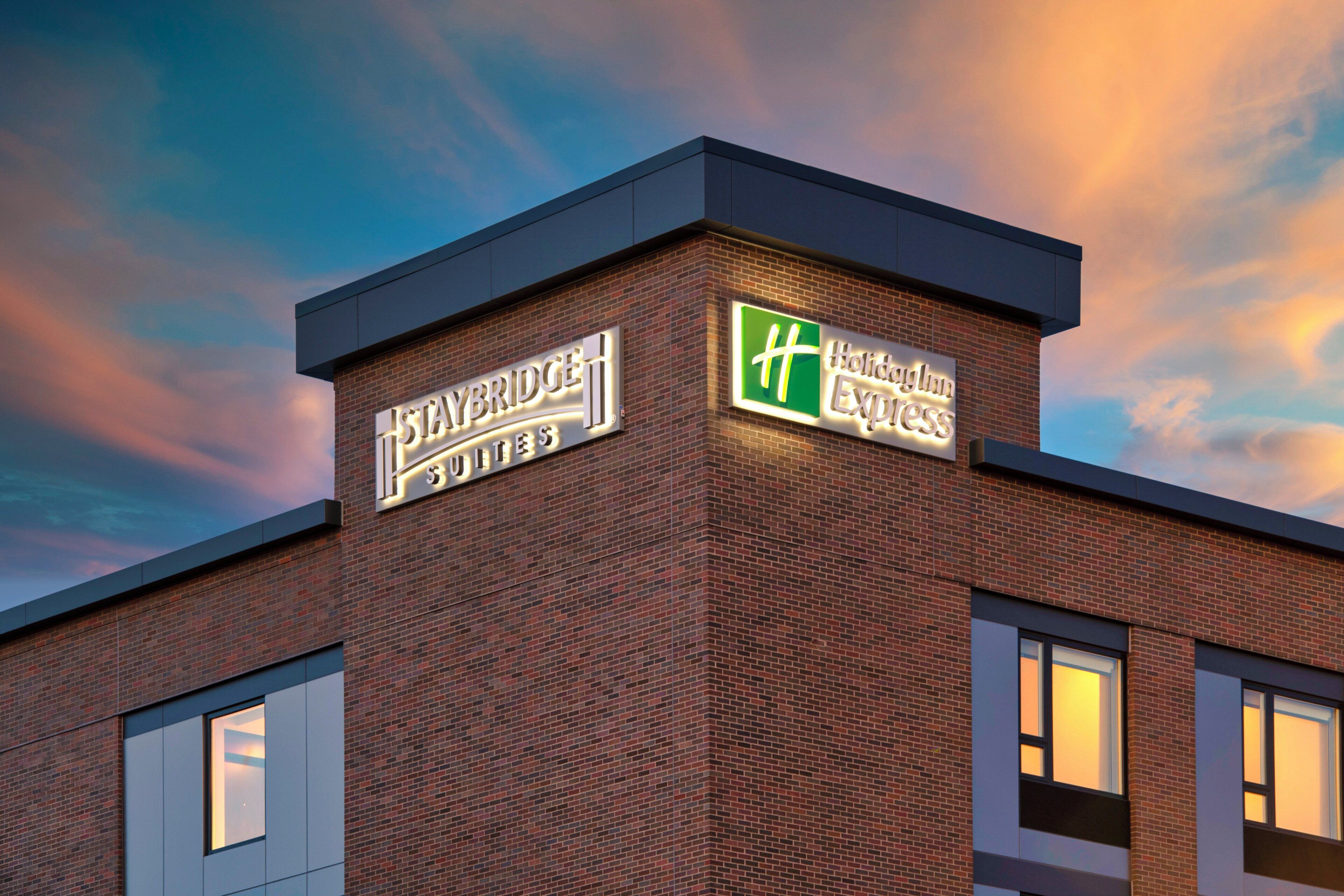 A building with a brick facade and two illuminated signs, one for a hotel and another for a Holiday Inn Express.