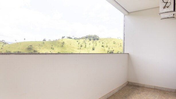 A balcony with a view of a green hillside. - Pousada Senhora do Carmo (Itabira)