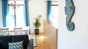 A living room with a black sofa, a wooden coffee table, a chandelier, and a potted plant. - Central. High speed WIFI & FREE Parking (Lisboa)