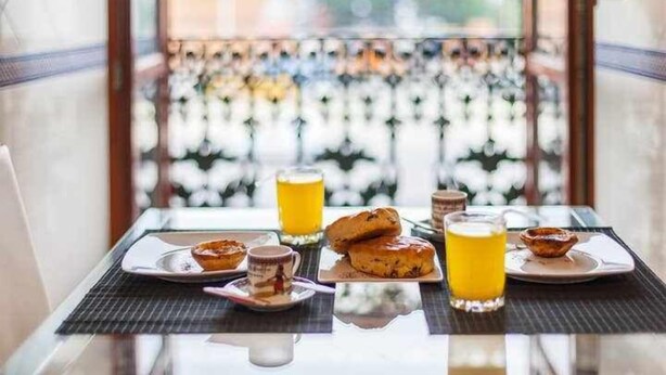 Et morgenbord med kager, et glas appelsinjuice og en kop.