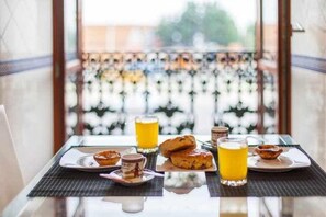 Ein Frühstückstisch mit Gebäck, einem Glas Orangensaft und einer Tasse.