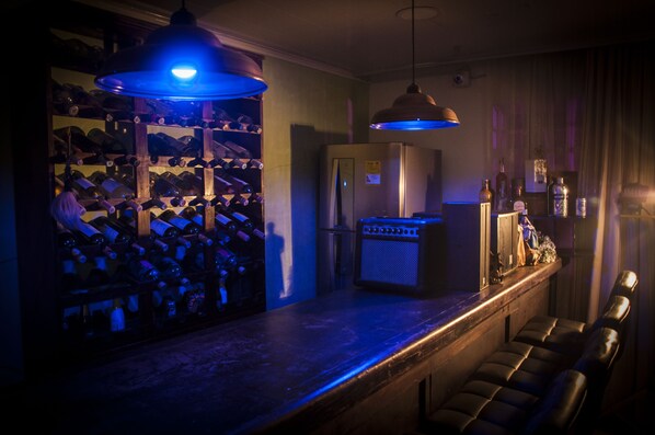 Zona de bar con botellero, refrigerador, juke box y taburetes de cuero.