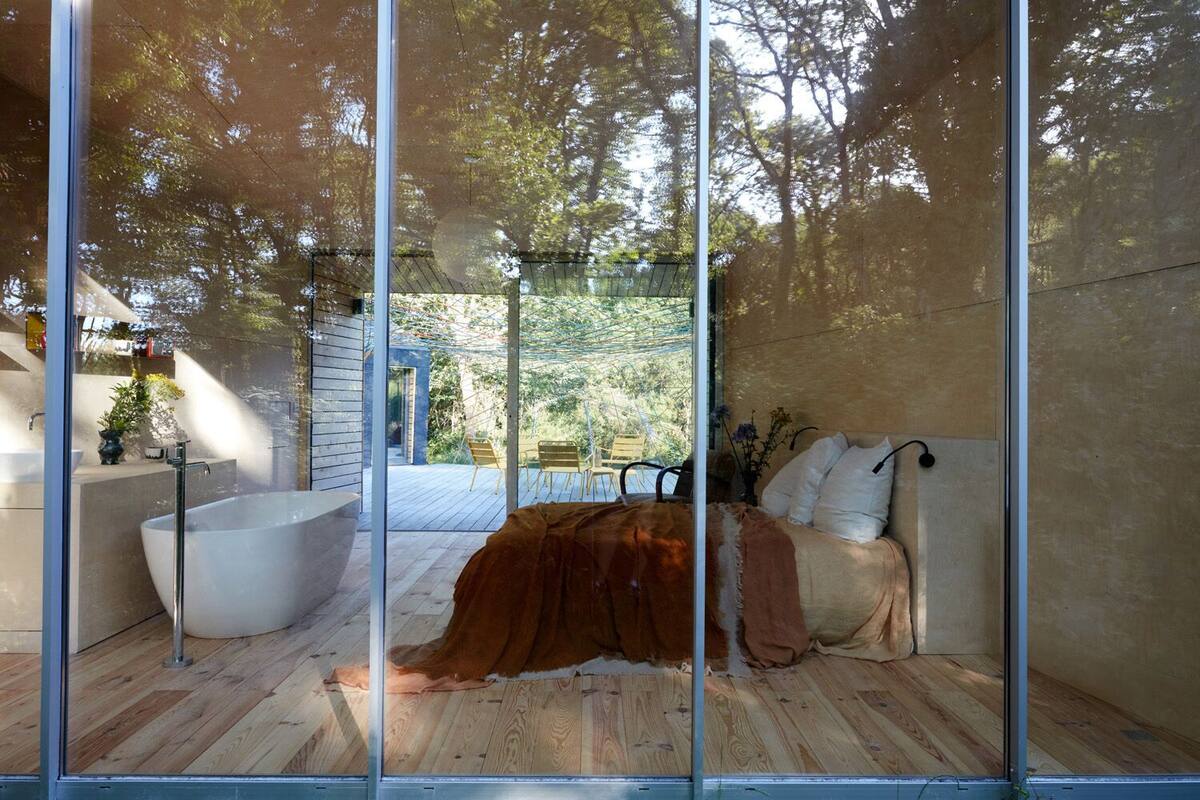 A modern bathroom with a large bathtub, a wooden floor, and a glass partition.