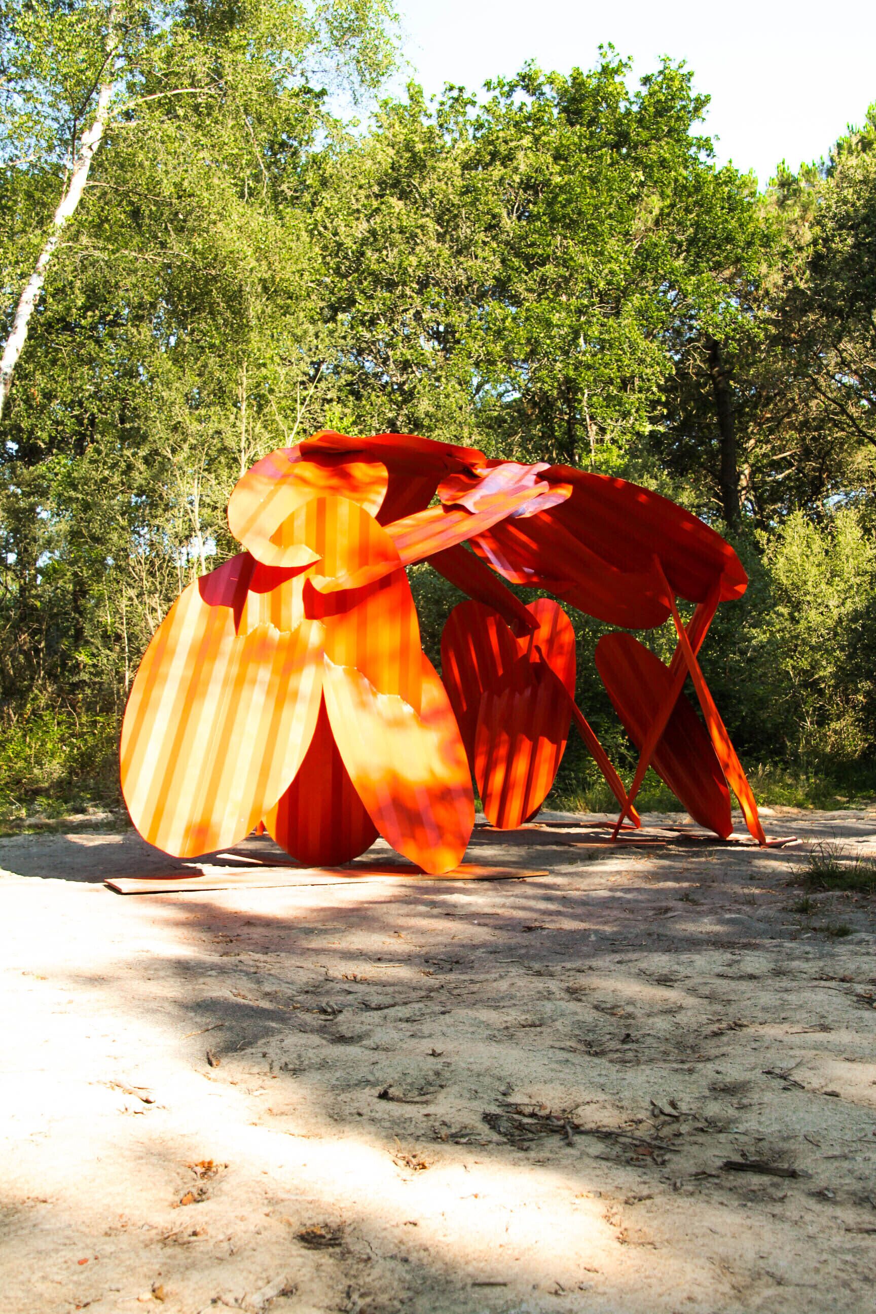 Une sculpture exposée en plein air, avec des arbres en arrière-plan.