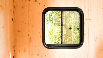 Un interior de madera con una ventana, una silla de mimbre y una mesita.