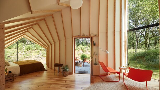 A cozy, naturally lit room with a sloped ceiling, wooden flooring, and a large window offering a view of the outdoors. - La Belle Folie (Ploemel)