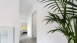 Ein modernes Hotelzimmer mit einem Bett, einem Nachttisch und einer großen Pflanze in einem Topf.
