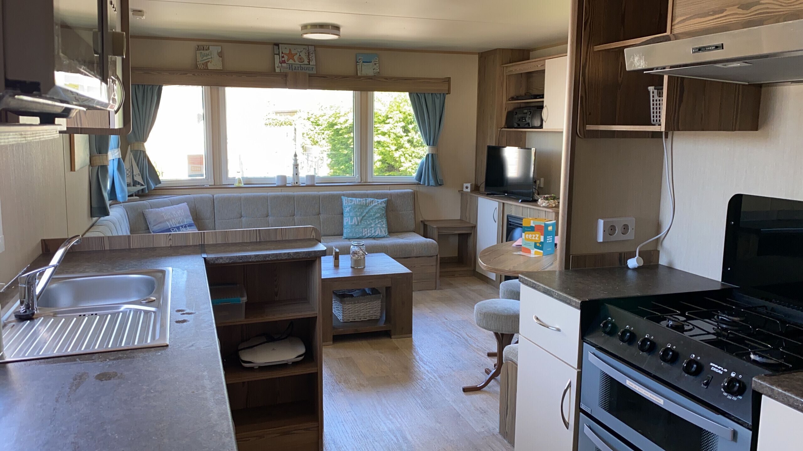 A compact kitchen with a stove, sink, and a dining area with a sofa.