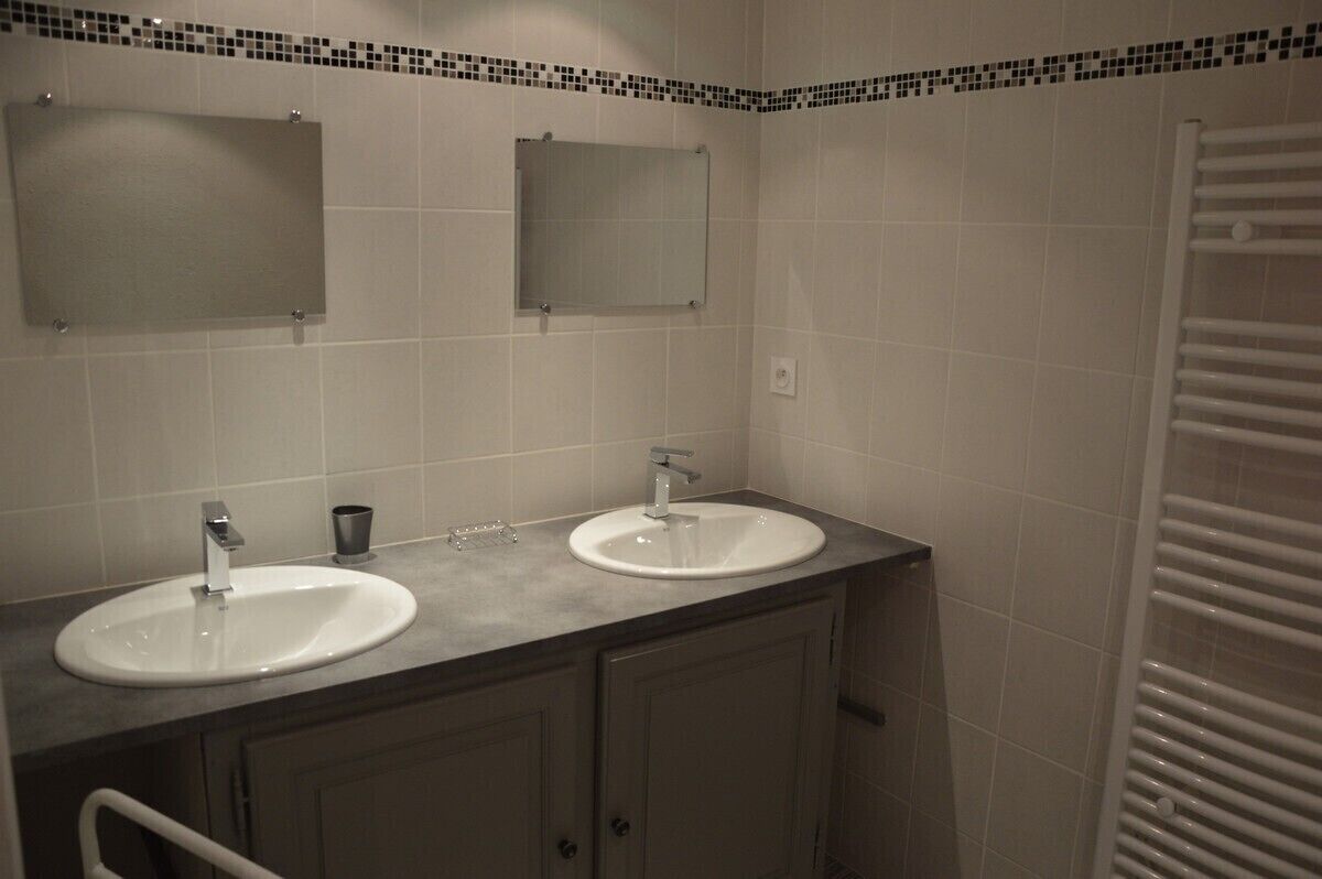 A bathroom with two sinks, a mirror, and a towel rack.