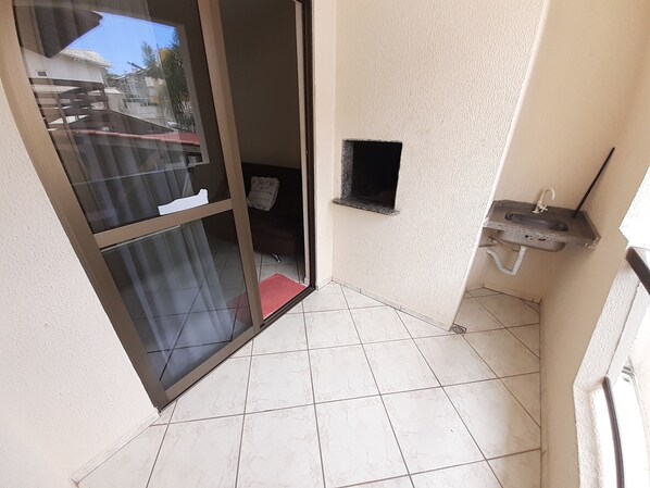 Un piccolo bagno piastrellato con un lavandino, una finestra e una porta che dà su un balcone.