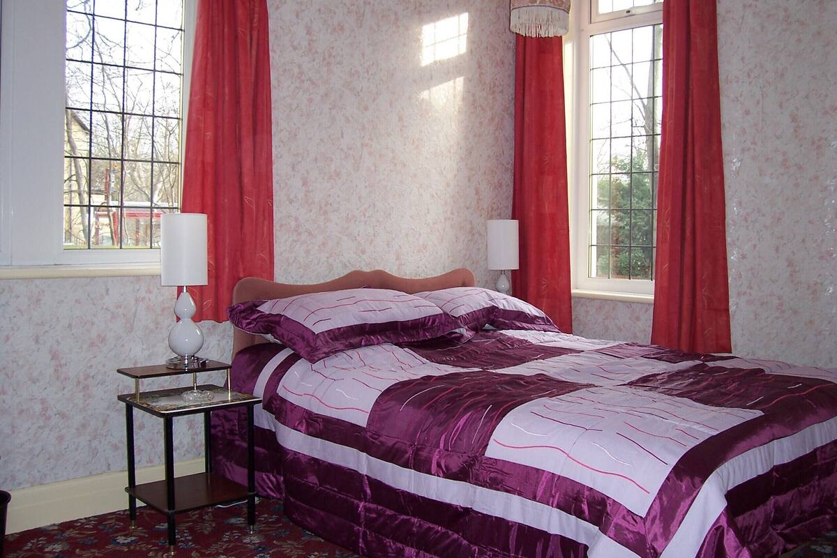 A bedroom with a bed, two bedside tables, and a window with curtains.
