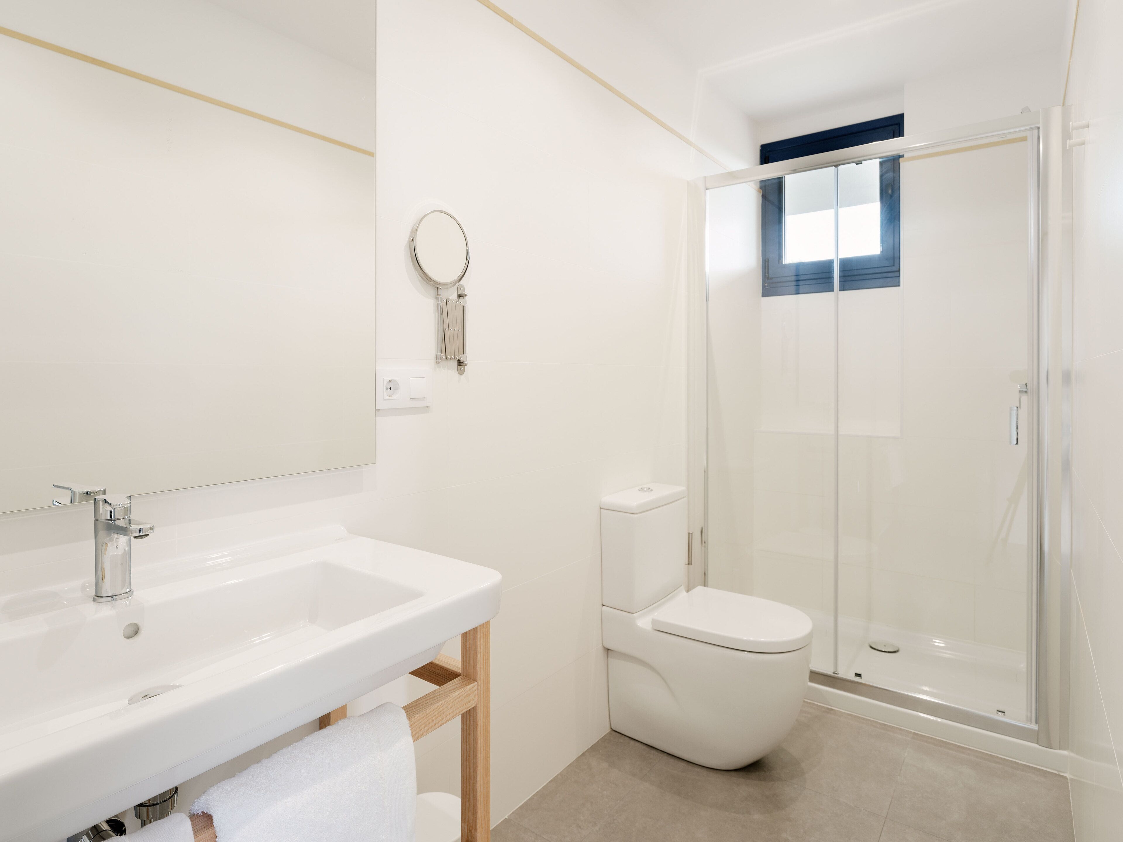 A modern bathroom with a white sink, mirror, and toilet.