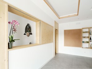 A modern interior with a wooden reception desk, a potted orchid, and a corkboard wall. - Apartamentos Ribeira Sacra (Parada de Sil)