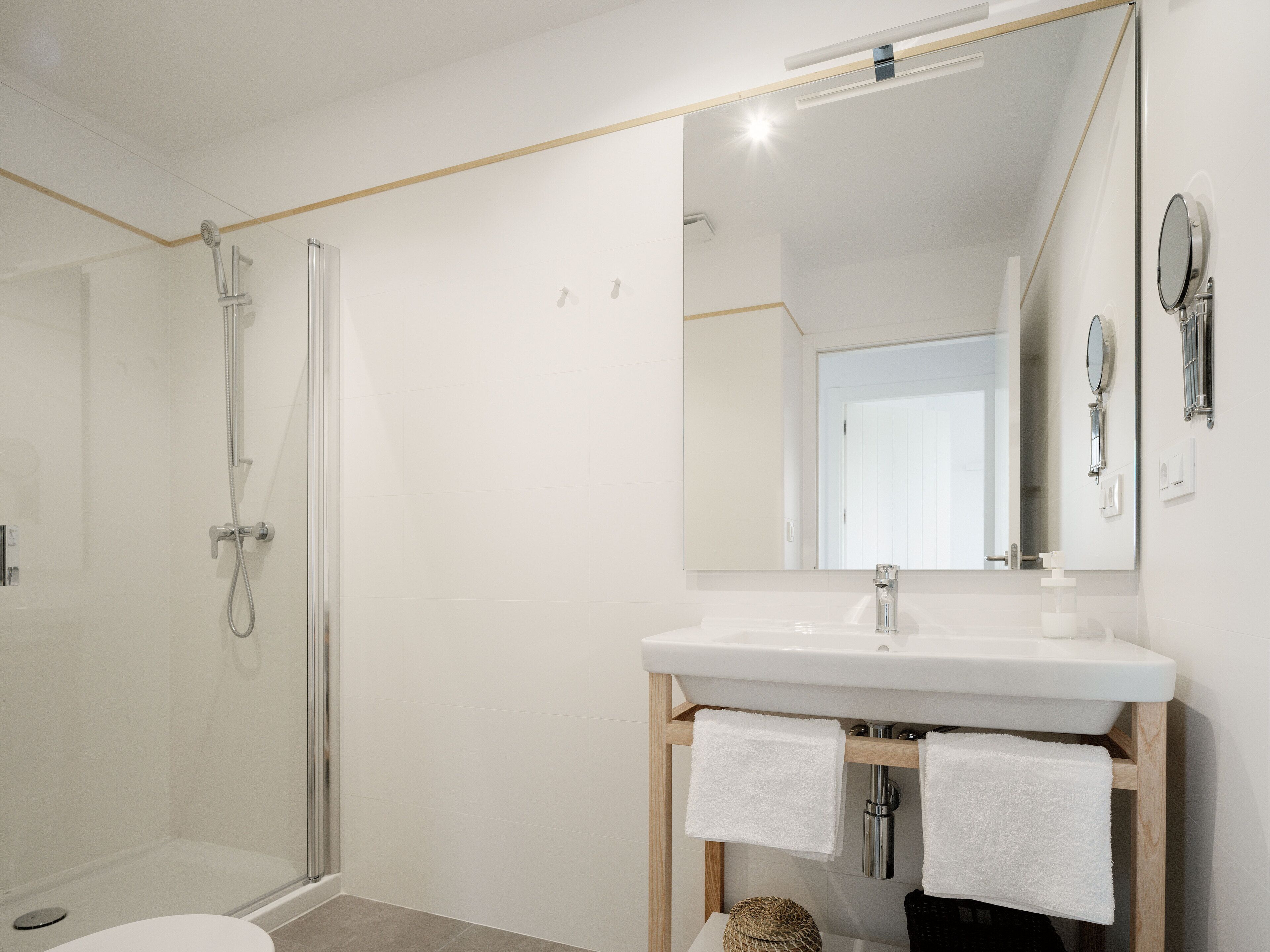 Une salle de bain moderne avec une douche à parois de verre, un lavabo blanc et un grand miroir.
