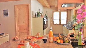 Eine Küche mit Holzausstattung, einem Kühlschrank und einem Essbereich mit Tisch für zwei Personen.