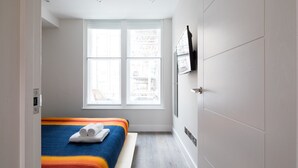 Ein Schlafzimmer mit Bett, Fenster und Tür.