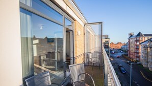 Ein Balkon mit Metallstühlen und einer Glastür, die zu einem Zimmer führt.
