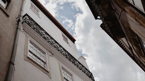 A building with white walls, multiple windows, and a black metal balcony railing.