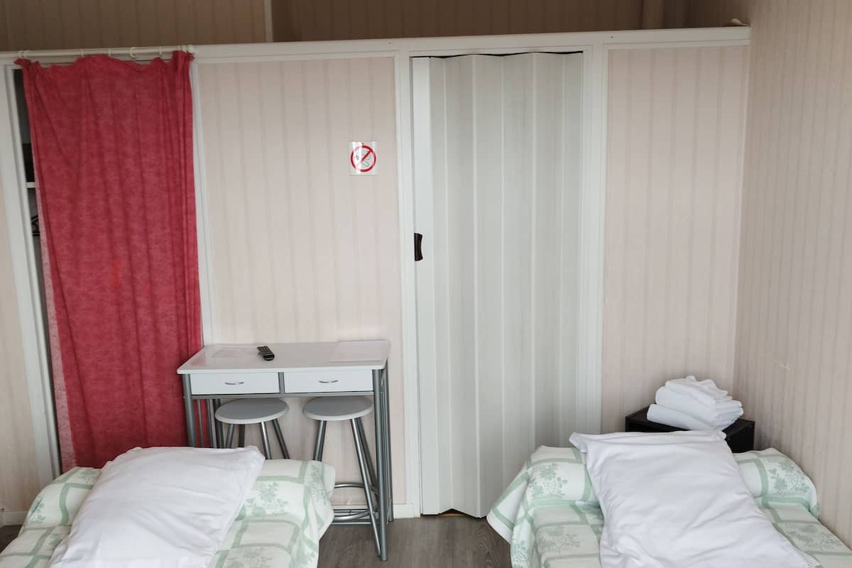 A hotel room with two beds, a desk, and a chair.