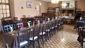 A dining area with multiple tables and chairs, a checkered floor, and a chandelier. - Le Lithana (Pontorson)