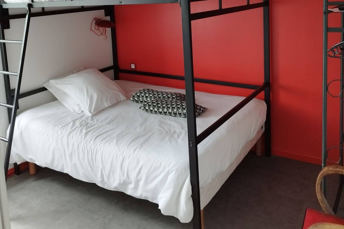 A bunk bed with white bedding in a room with red walls.