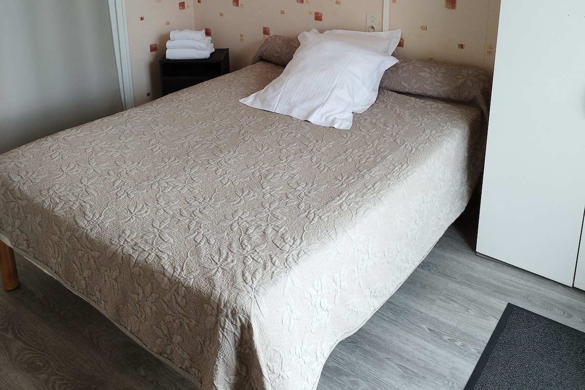 A hotel room with a bed, a nightstand, a wardrobe, and a curtain.