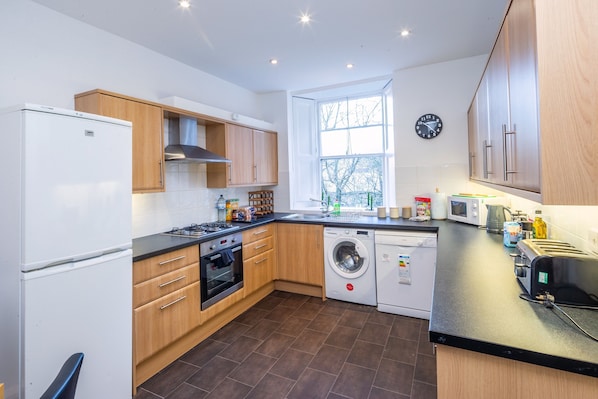 Kitchen features a clean and contemporary look with cabinetry, appliances, and a large window for natural light.