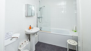 Une salle de bain moderne avec un lavabo blanc, un miroir, des toilettes et une douche.