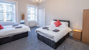 Une chambre à coucher avec deux lits, un lustre et de grandes fenêtres.