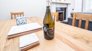 Une bouteille de vin Prosecco DOC sur une table en bois, avec un dessous de verre blanc et bleu à motifs et une pile de dessous de verre blancs.