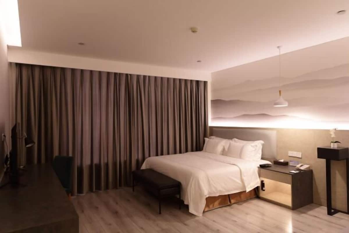 Een moderne hotelkamer met een groot bed, nachtkastje en een bureau met stoel.