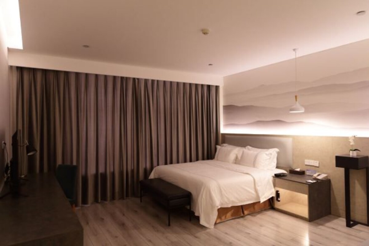 Una habitación de hotel moderna con una cama grande, una mesita de noche y un escritorio con silla.